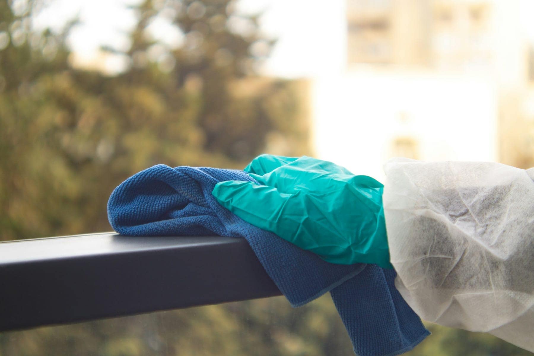 Behandschuhte Hand reinigt ein Geländer