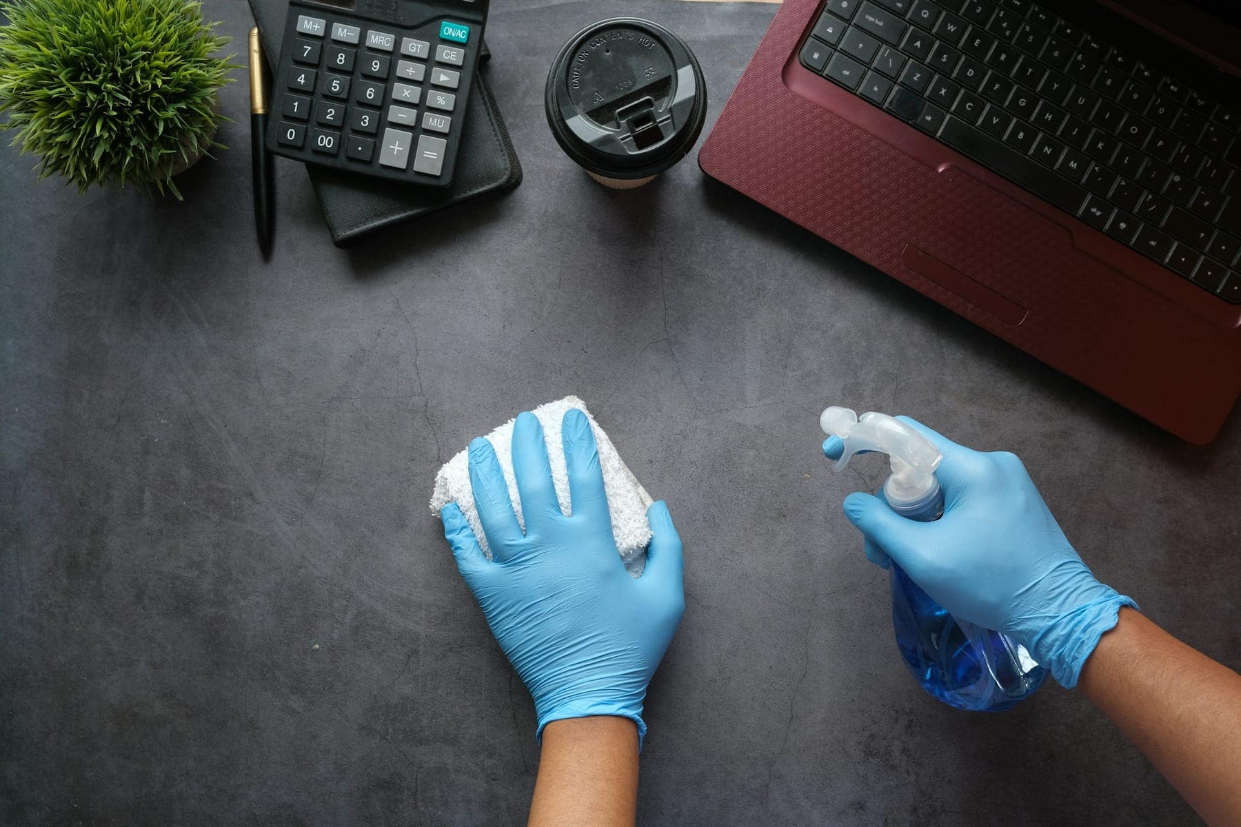 Behandschuhte Hände reinigen eine Arbeitsfläche